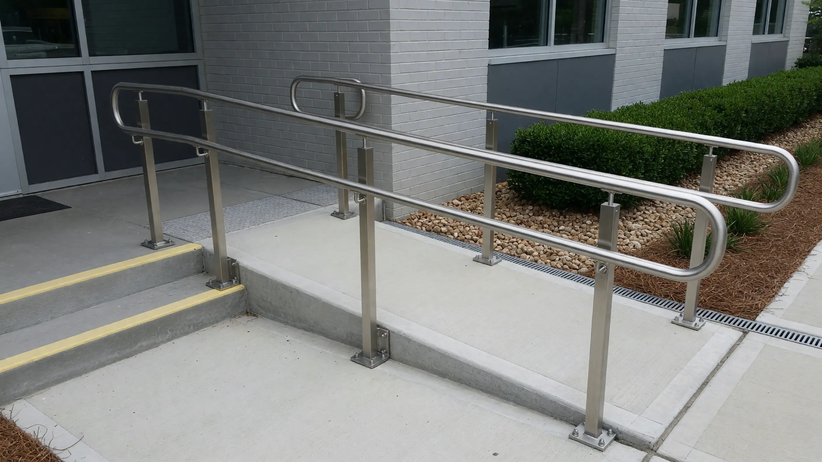 Stainless ADA handrail following a clean commercial ramp and landing