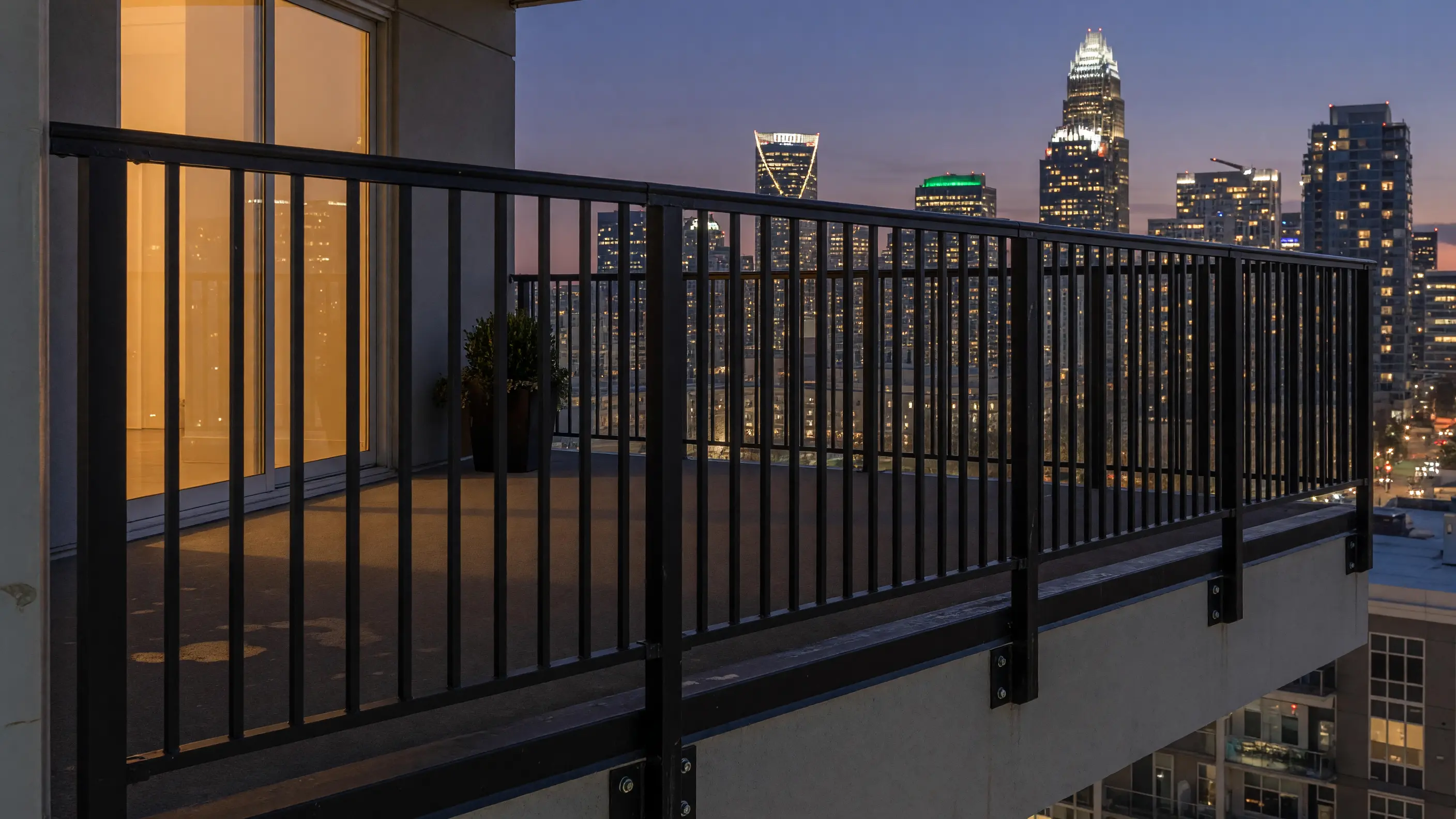 Black aluminum balcony railing on an uptown Charlotte condo terrace with the skyline at dusk