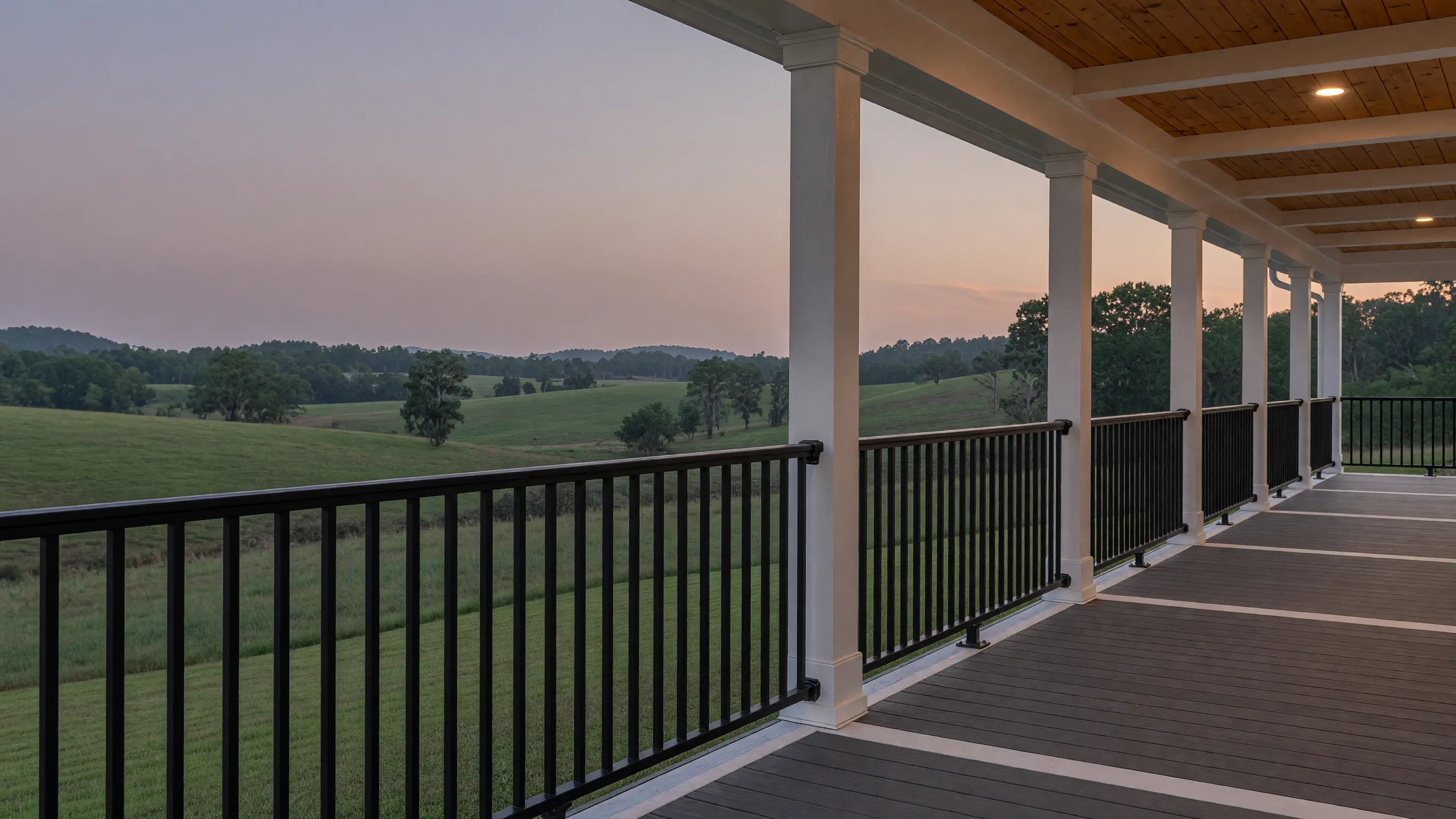 Black aluminum picket railing running the length of a wraparound farmhouse porch