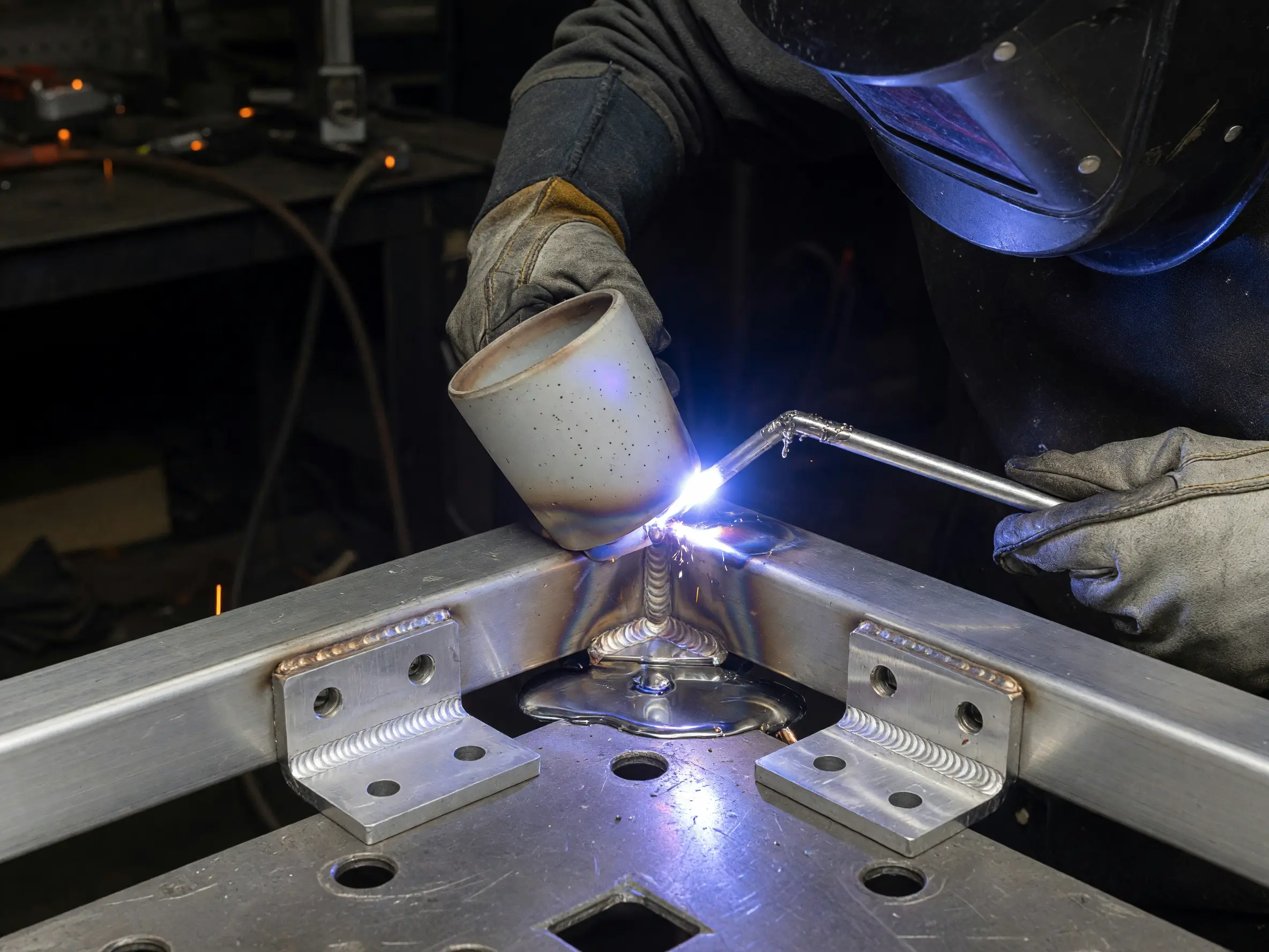 Close-up of a gloved fabricator TIG welding an aluminum railing joint